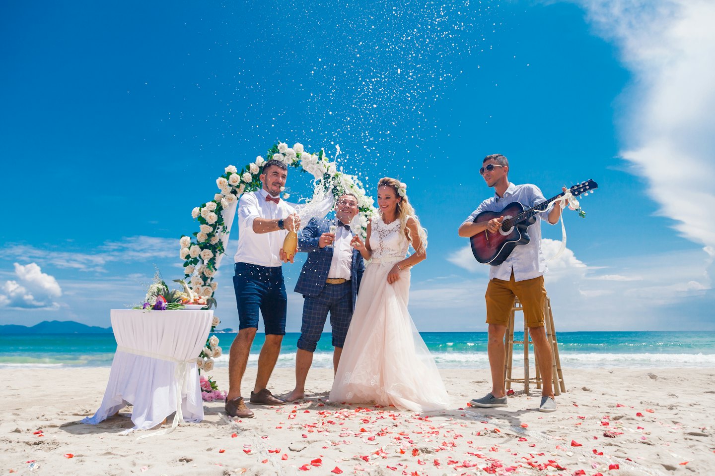 Coppia festeggia un matrimonio in spiaggia con champagne e musica di chitarra.