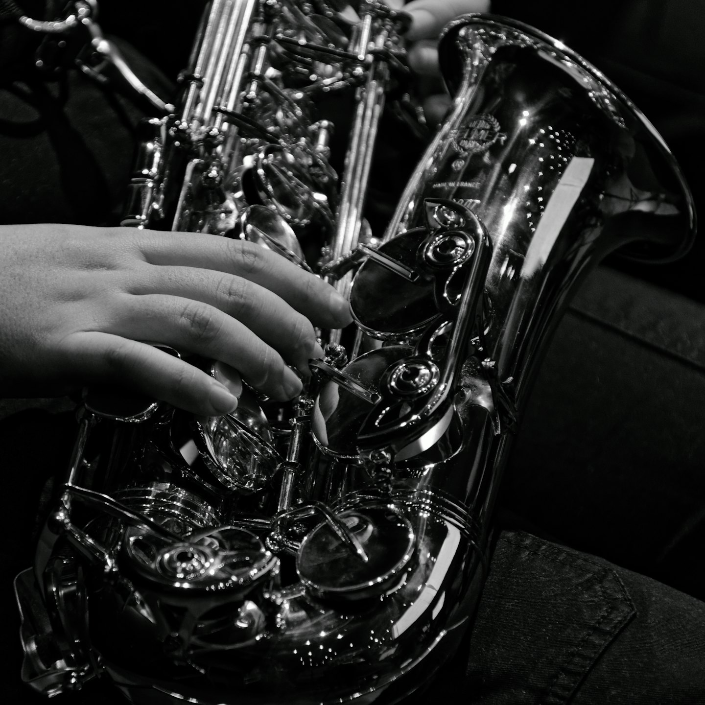 Dita di un musicista che premono i tasti di un sassofono argentato.
